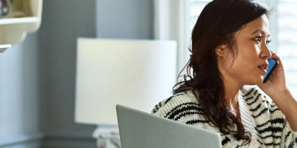 femme assise devant un ordinateur portable appelant quelqu'un au téléphone